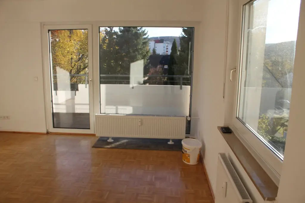 Helles Wohnzimmer mit großen Fenstern und Parkettboden
