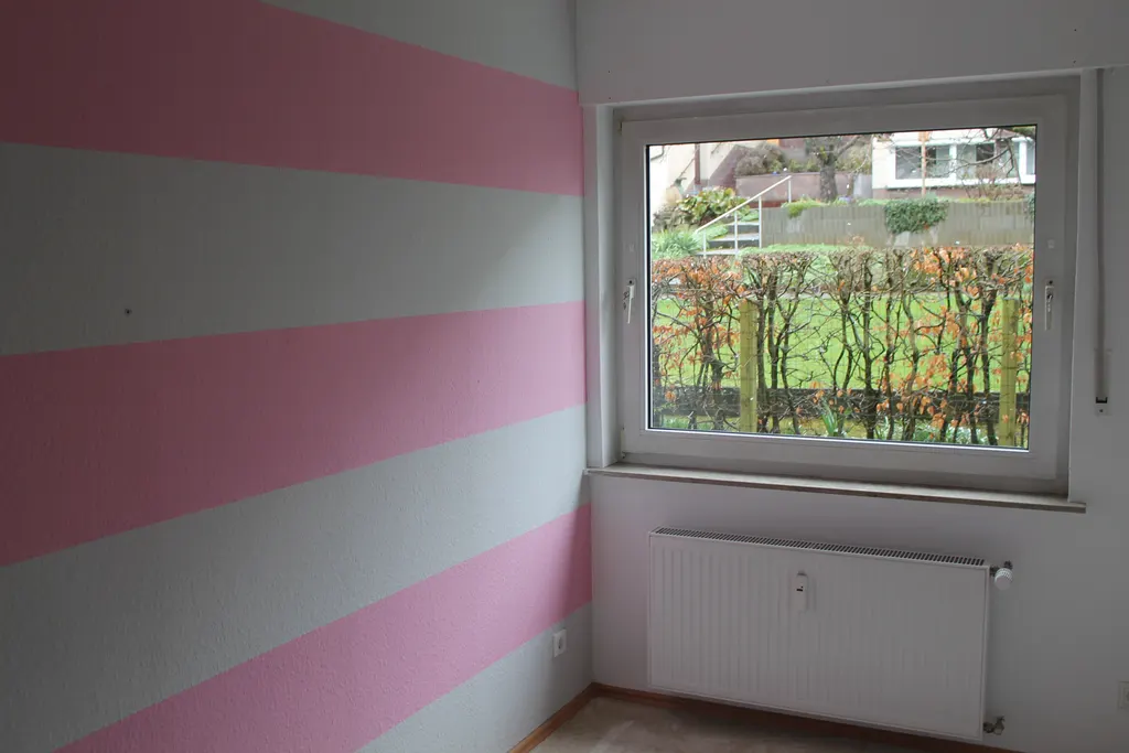 Zimmer mit Fenster und Blick auf die begrünte Gartenseite